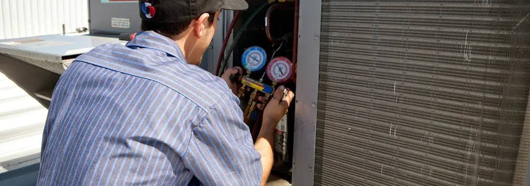 HVAC technician servicing a condenser unit in Prairie Grove